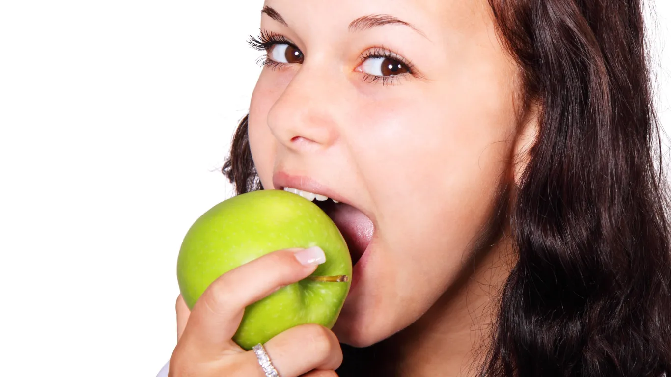 青リンゴをよく噛んで食べる女性